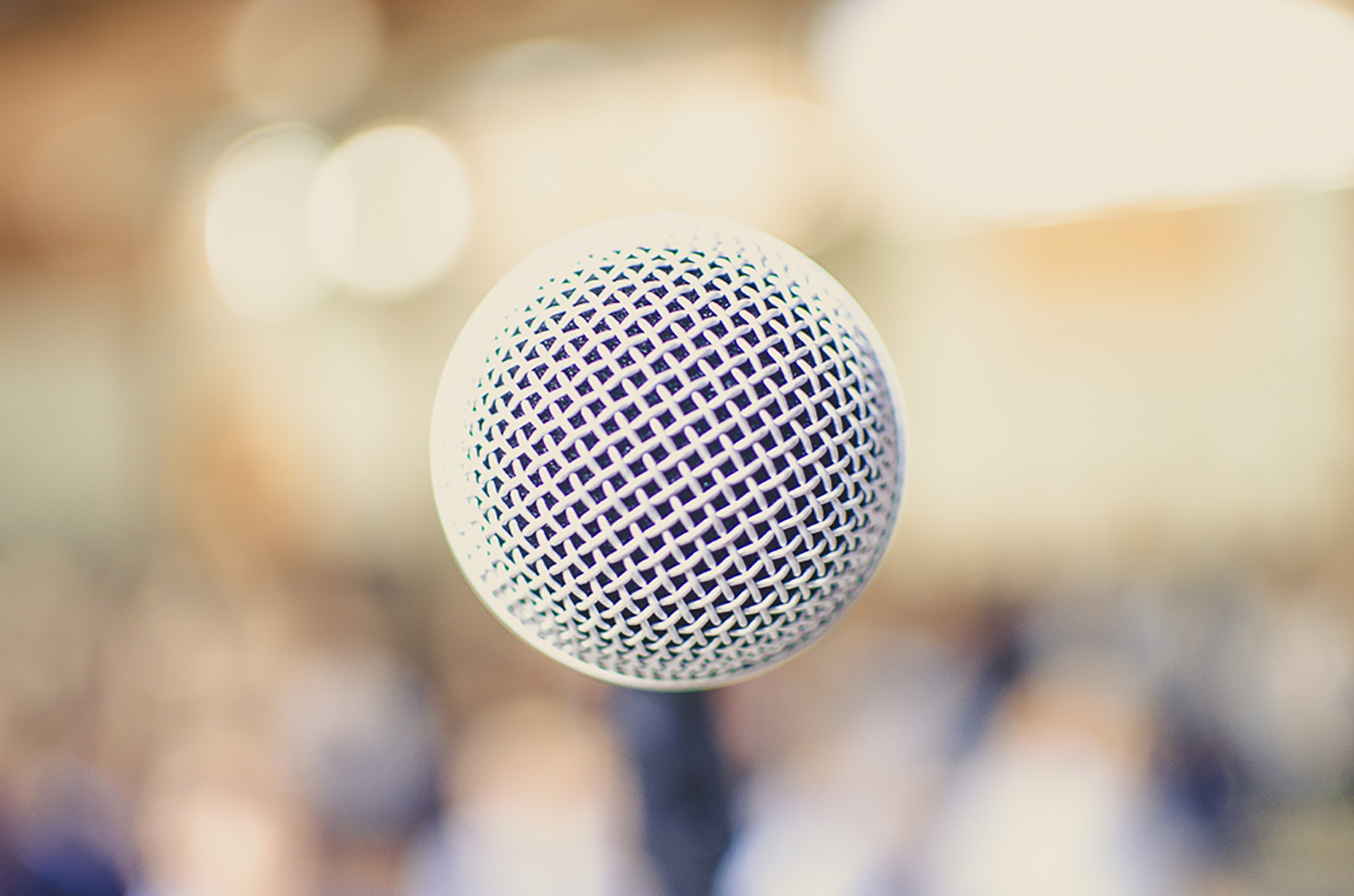 The top of a microphone and a hazy yellow background.